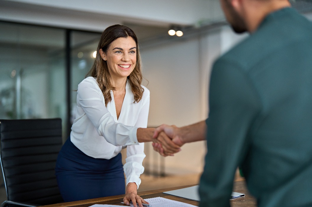 Eine Managerin mittleren Alters schüttelt einem männlichen Kunden oder Geschäftspartner die Hand.