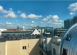 Stadtlandschaft mit modernen Gebäuden und Wolken am blauen Himmel bei Tageslicht.
