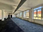 Weiträumiges, leeres Büro mit Teppichboden, weiß gestrichen. Große Fenster lassen viel Licht herein.