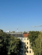 Ansicht von Gebäuden und Bäumen mit dem Berliner Fernsehturm im Hintergrund unter klarem Himmel.