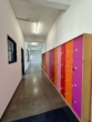 Flur mit bunten Schließfächern in Orange und Pink; weiße Wände, grauer Boden, moderne Gestaltung.