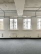 Leerer Raum mit drei Fenstern, weißen Wänden, grauem Teppich und sichtbarer Decke.