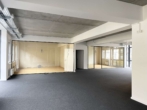 Leerer Büroraum mit grauem Teppichboden und Glastrennwänden, moderne industrielle Decke.