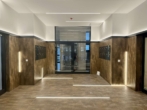 Moderne, beleuchtete Lobby mit braunen Wänden und glänzendem Boden, keine Personen sichtbar.