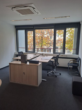 Ein leeres Büro mit einem Schreibtisch, Bürostuhl und großem Fenster mit Blick auf Herbstbäume.